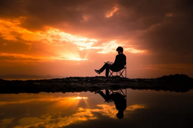 man-reading-by-water